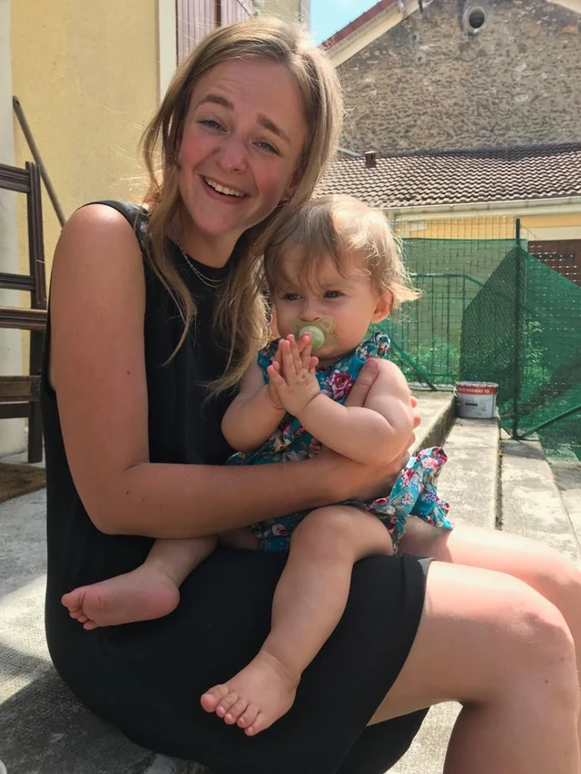 An adult holding a small child while seated outdoors.