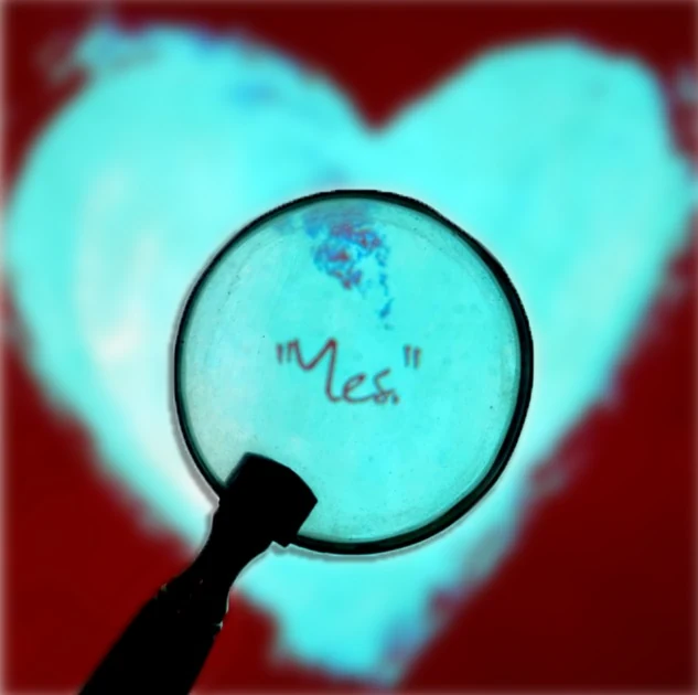A magnifying glass held over handwriting against a turquoise heart shape.